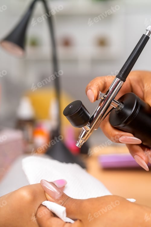 Vista previa: Manicurist applying nail polish with airbrush tool