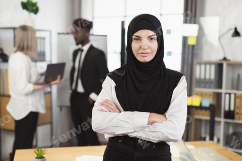 Preview: Woman in hijab posing at office with coworkers on background