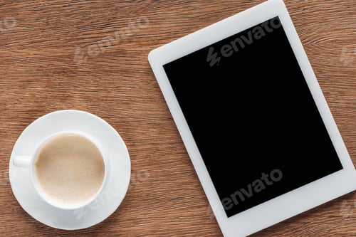 Preview: Top view of coffee cup and digital tablet with blank screen on wooden background