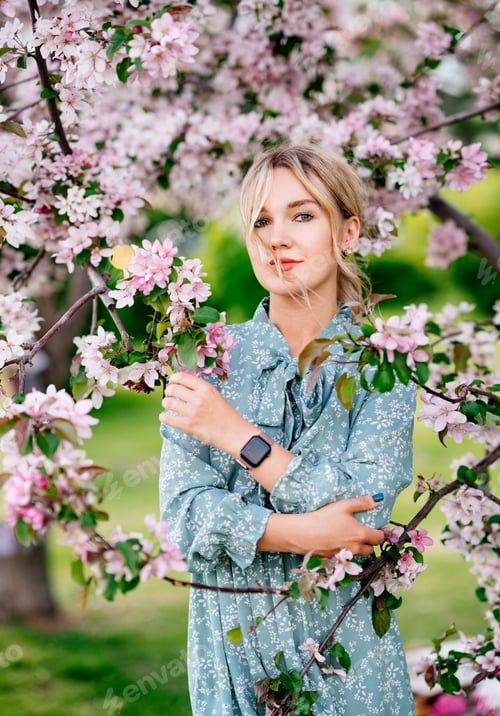 Preview: Portrait of a woman in a blue dress among pink flowers.