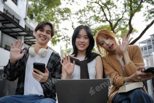 Preview: Three young people happily waving and smiling during a video call on a laptop.