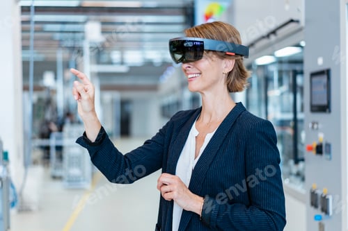 Preview: Smiling businesswoman wearing AR glasses in a modern factory