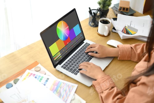 Preview: Close up of designer or entrepreneur reviewing color swatches while working on a laptop