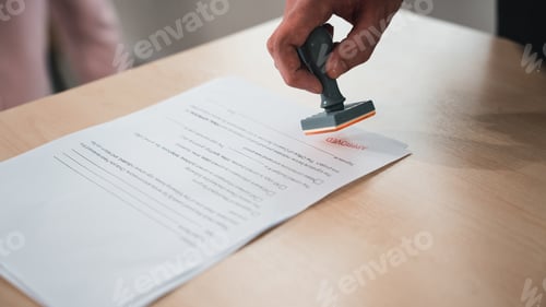 Preview: Businessman hand stamping an approved stamp on a text document.