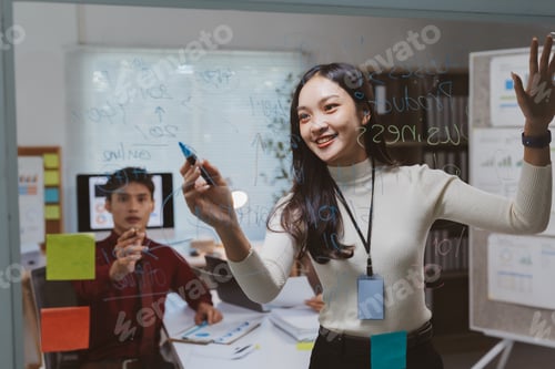 Preview: Businesswoman writing strategy on glass board during presentation
