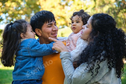 Preview: Latin happy family with two kids together in a park.