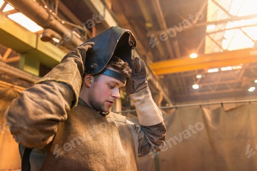 Welder Putting on Protective Gear at Work