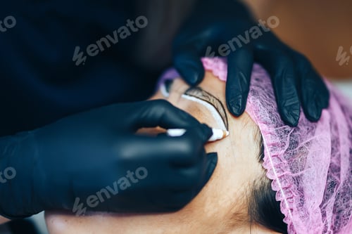 Preview: master prepare for Microblading, micropigmentation eyebrows. woman drow on customer eyebrow white