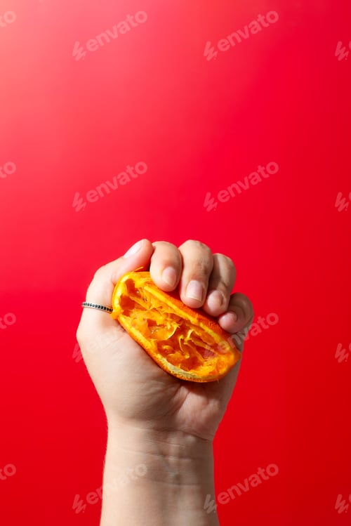 Preview: An individual is grasping a piece of orange while sporting an accessory on their wrist