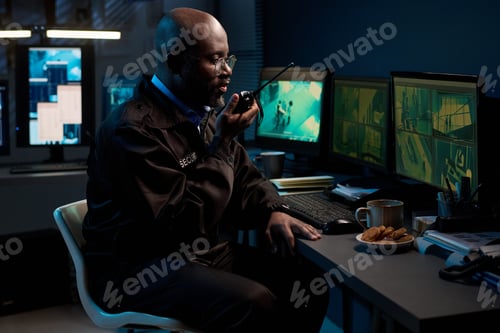 Preview: Black Man Monitoring Security Cameras While Speaking into Walkie Talkie