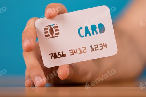 Preview: Closeup shot of a person holding a credit card paper cut-out on a blue blurry background