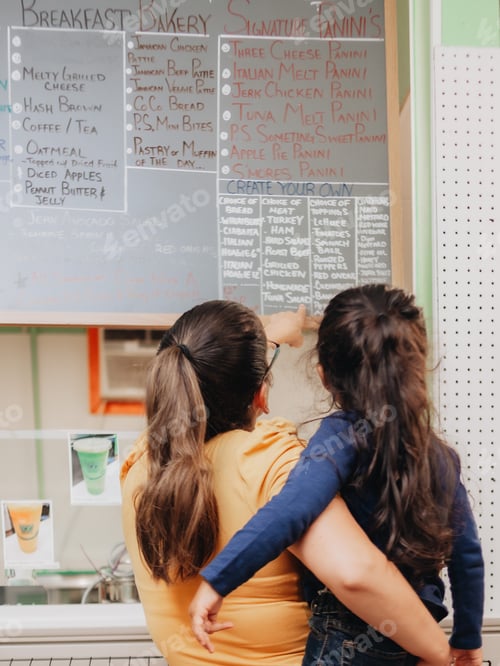 Preview: Mother and daughter at a local small business choosing food items from menu