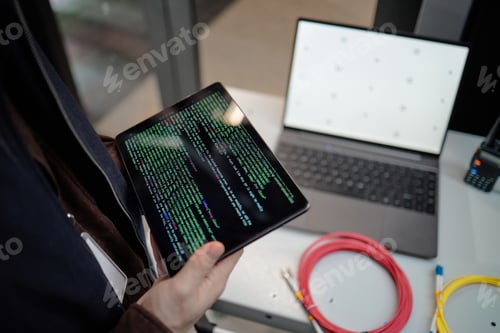 Preview: Young Adult Man Holding Tablet Displaying Code near Laptop Working