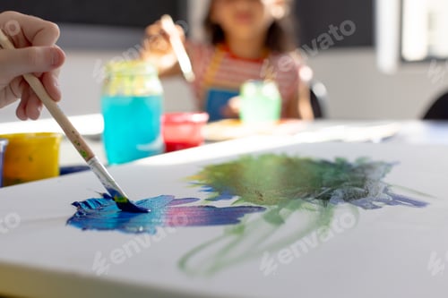 Preview: In school art class, biracial girl and a Caucasian girl, both young, painting together