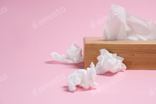 Preview: Holder with paper tissues and used crumpled napkins on pink background