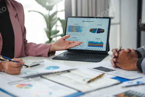 Preview: Businesswoman pointing at tablet showing summary report during meeting