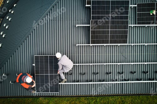 Preview: Men workers installing solar panels on roof of house.
