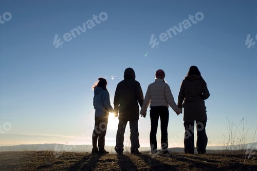 Preview: Friends standing together watching a sunset.