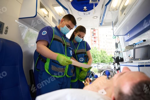 Preview: Team of paramedics makes a cardiogram to man in ambulance