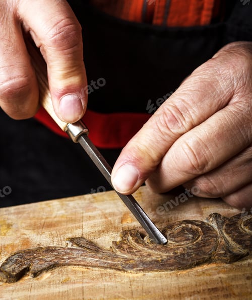 Preview: Close up of senior carpenter working with a hammer, chisel and wood carving tools.