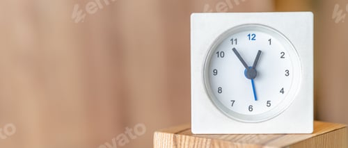 Preview: White clock on a wooden surface. Blurred wooden background. Copy space