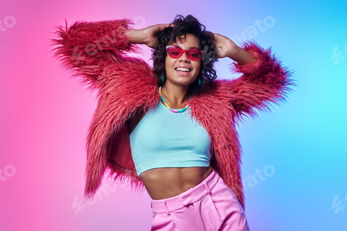 Preview: Happy African woman in trendy clothes holding hands in hair