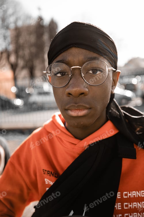 Preview: generation z young black teenager wearing eyeglasses and an orange hoodie