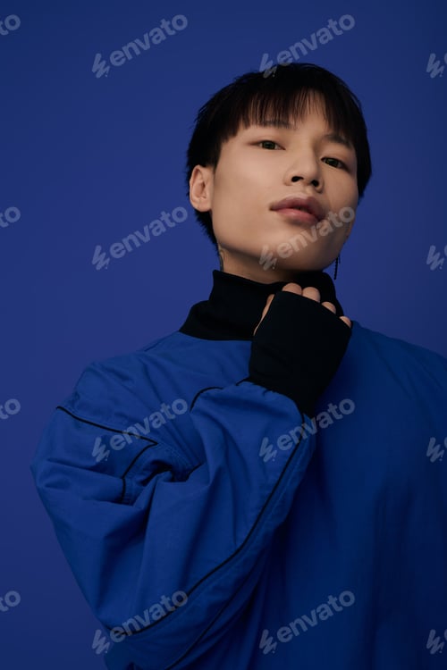 Preview: Captivating young asian man posing confidently against a vibrant blue backdrop