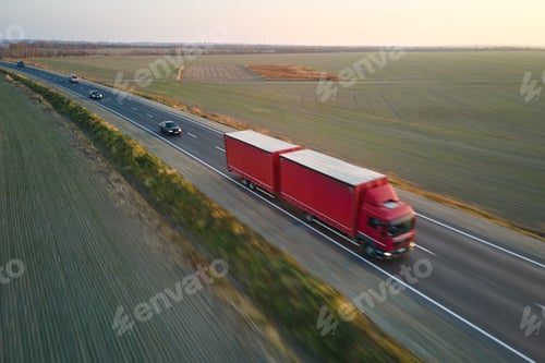 Preview: Aerial view of blurred fast moving semi-truck with cargo trailer driving on highway hauling goods in