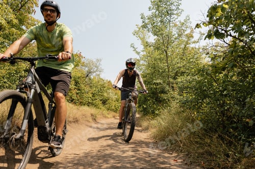 Preview: Two cyclists riding bikes on a forest trail in a natural environment