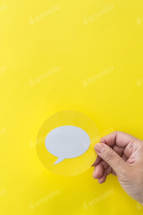 Preview: Vertical shot of a male hand holding a speech balloon shape card on a yellow background