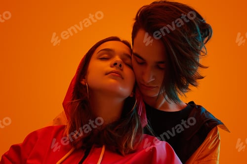 Preview: Teen couple hugging under orange neon light