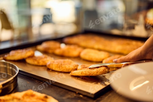 Preview: A female baker holding a plate and taking a freshly baked pastry.