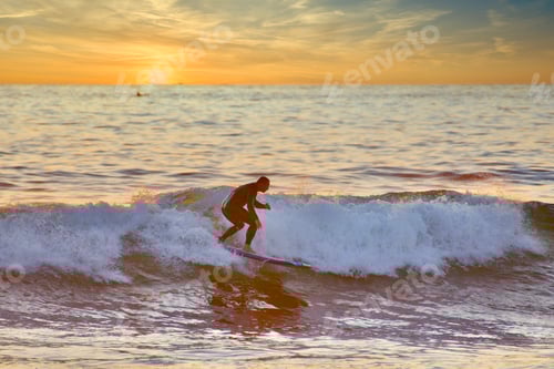A surfer takes an epic ride on a beautiful day on the Pacific Ocean waves during sunset in San Diego