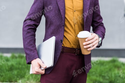 Preview: Cropped view of businessman holding laptop and paper cup