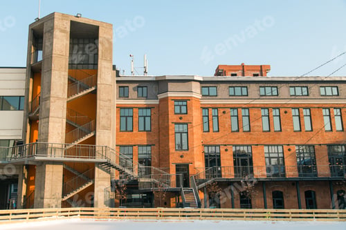 Preview: Facade of red brick building with outdoor iron stairs. Industrial building converted into offices