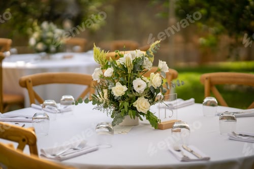 Preview: Selective focus shot of a floral centerpiece on a wooden table at an outdoor party