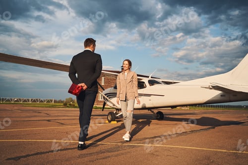 Preview: Beautiful couple in love standing near plane at airfield