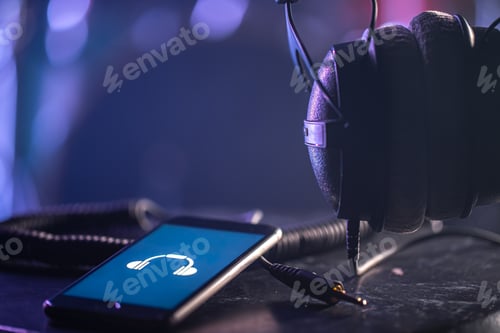 Preview: Musical background with a phone and headphones on a dark background.