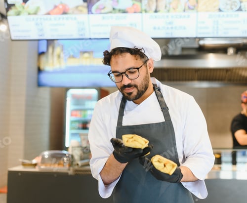 Preview: Chef holding shawarma examining food quality in restaurant kitchen
