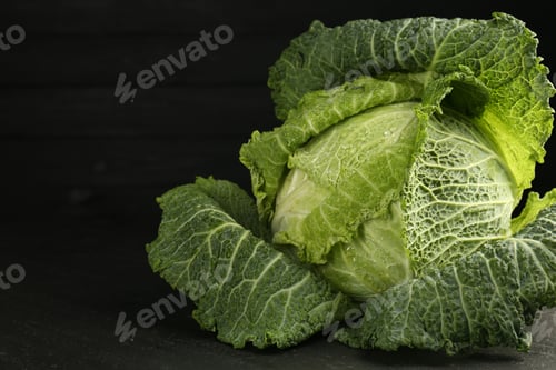 Preview: Fresh Savoy cabbage on black table, closeup. Space for text