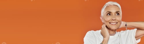 Preview: Confident Woman With Short Hair in Stylish Attire Against Vibrant Orange Background