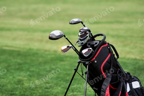 Preview: Photo of golf bag with sticks standing on the green lawn. Close up view