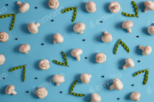 Preview: Overhead shot of edible mushrooms, ripe green peas and peppercorns isolated on blue background. Vege