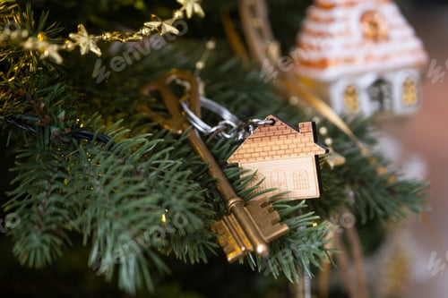 Preview: Key to the house with a keychain is hanging on the Christmas tree. A gift for New Year, Christmas