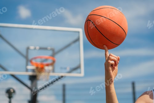 Preview: A close-up of a basketball player spinning a ball on their finger, with the hoop blurred in the back