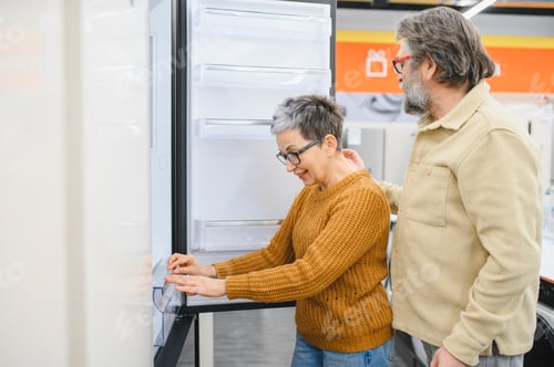 Preview: Senior couple choosing new kitchen refrigerator in appliance store