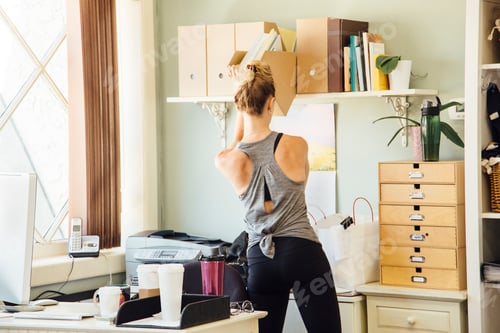 Preview: Woman in office taking paperwork from shelf
