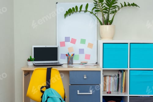 Preview: Workspace with desk and chair and open laptop computer in modern room for children.