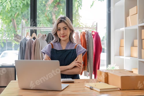 Preview: Asian beautiful woman entrepreneur of online sell clothing with laptop and notebook on desk in home